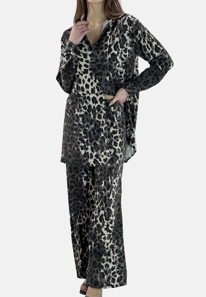 Tenue imprimé léopard en noir et crème, fabriquée dans un tissu lisse. Comprend une chemise à manches longues et un pantalon à jambes larges, avec une coupe décontractée.