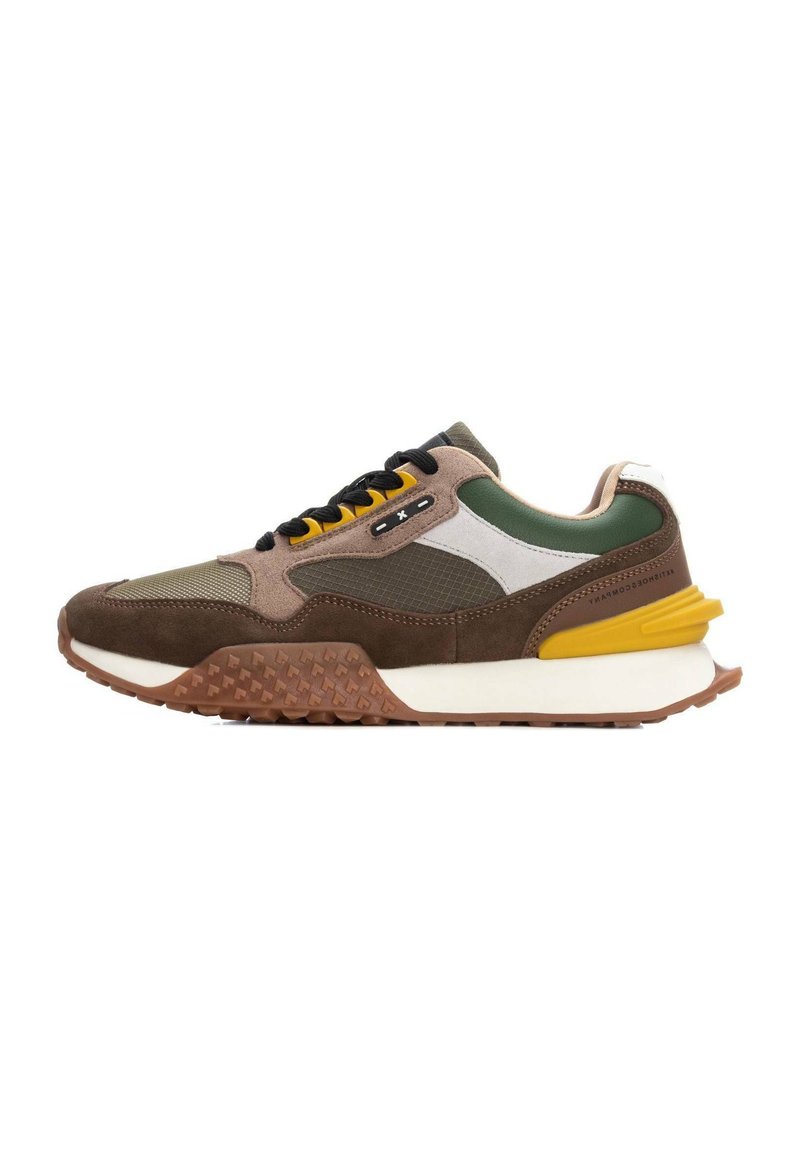 Zapatilla que presenta una mezcla de ante marrón, acentos verdes y talón amarillo. Detalles de malla y texturizados en los laterales, con una suela de goma estampada.