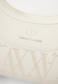 Hvit strukturelt lærveske med perforert 'A/X'- mønster og preget 'Armani Exchange'-logo. Glatte kanter og minimalistisk design.