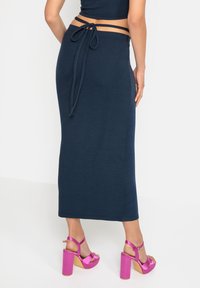Navy ribbed maxi-hame, jossa on solmittava vyötärö ja kapea malli, yhdistettynä vaaleanpunaisiin platform-sandaaleihin.