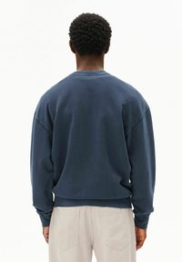 Marineblauwe sweatshirt met een ontspannen pasvorm, verlaagde schouders en geribbelde manchetten. Katoenmengstof met een gladde textuur en minimale stiksels.
