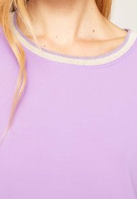 Levandulový top s jemnou a hladkou texturou a kulatým výstřihem, který má límec se metalickým lemem.