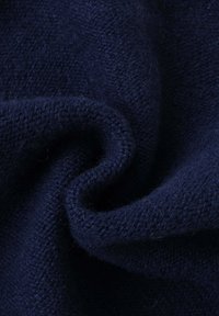 Tissu bleu marine avec une texture tissée, présentant des fibres douces et une surface légèrement duveteuse, plié pour révéler de la profondeur et de la chaleur.