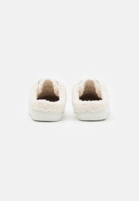 Ein Paar weiße Slipper mit dickem, flauschigem Fleecefutter und weißen Sohlen, von hinten auf einem weißen Hintergrund gezeigt.