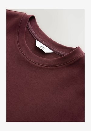 Sweatshirt bordeaux à col rond fabriqué en mélange de coton doux, doté d'une texture lisse, d'une coupe régulière et d'une étiquette de marque visible sur le col.