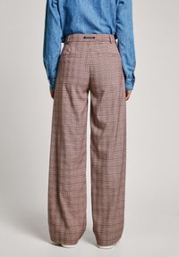 Vida byxor med vida ben i rutig mönster, med grå och röda linjer. Tillverkade av ett mönstrat tyg, med midjeband och bakfickor.