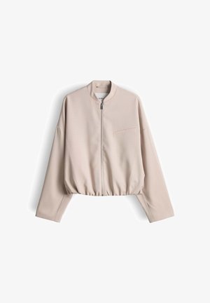 Lichtbeige cropped jack met lange mouwen, rits aan de voorkant, ronde hals en een klein borstzakje, weergegeven op een witte achtergrond.