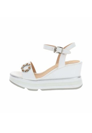 Sandale à talon compensé blanc avec bride à la cheville, boucle argentée, décoration circulaire perlée sur la bride des orteils et semelle épaisse superposée.