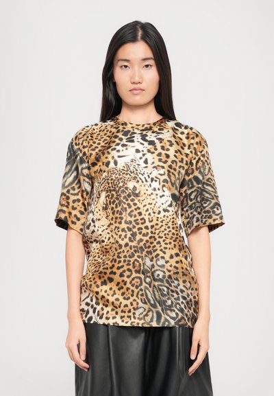 Leopardmuster T-Shirt mit kurzen Ärmeln, aus einem glatten, glänzenden Stoff in Braun-, Schwarz- und Cremetönen, kombiniert mit einem schwarzen Rock.