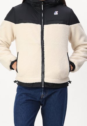 Hvid og sort zip-up jakke med fleece-krop, nylon-skuldrer, elastiske manchetter, sidelommer og justerbar kant. Logo på brystområdet.