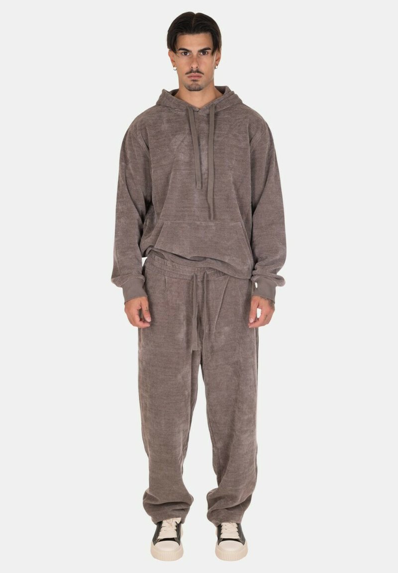 Felpa con cappuccio in tessuto di spugna grigio con tasca anteriore, abbinata a pantaloni relax-fit coordinati. Presenta cintura con cordino e polsini a costine.