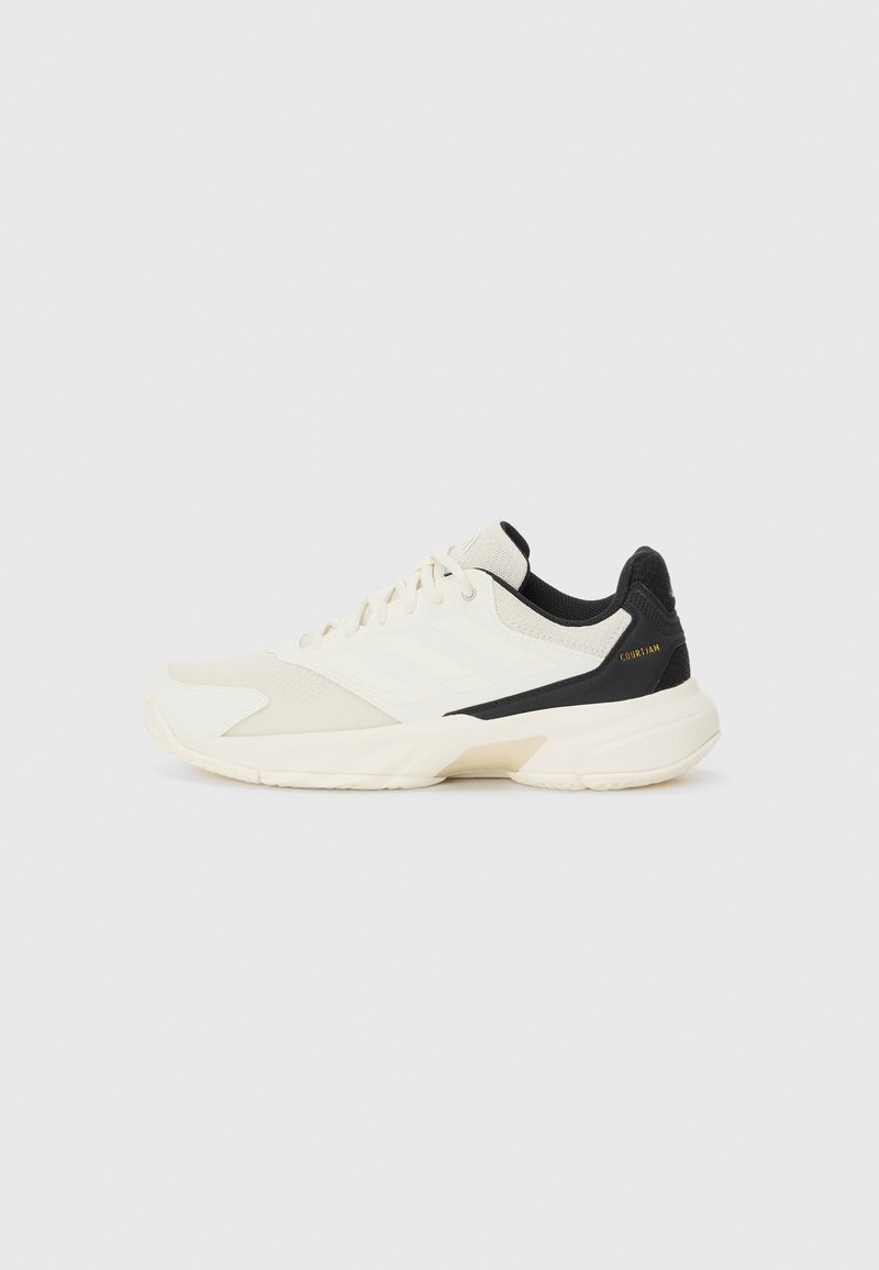 Sportschuhe mit einem Obermaterial in Cremefarbe und strukturierten Akzenten, schwarzem Fersenschutz und weißen Branding-Details. Gummisohle mit glatter Oberfläche.