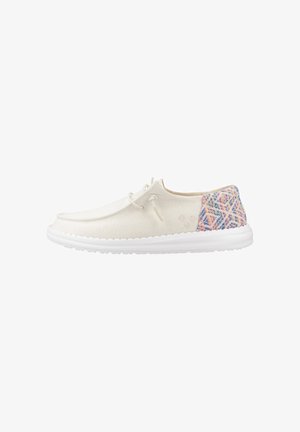 Zapato casual blanco con cordones, panel trasero tejido multicolor y suela blanca gruesa, visto de perfil izquierdo sobre fondo blanco.