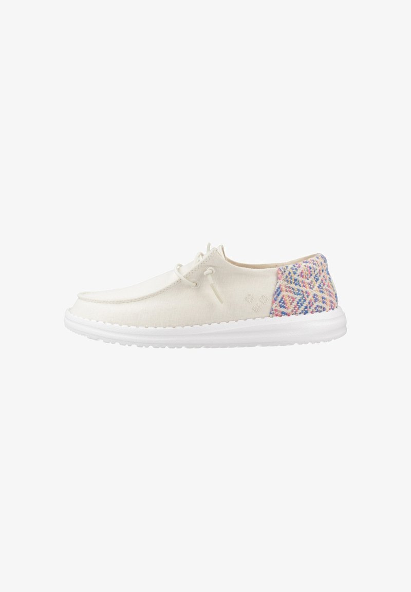 Zapato casual blanco con cordones, panel trasero tejido multicolor y suela blanca gruesa, visto de perfil izquierdo sobre fondo blanco.