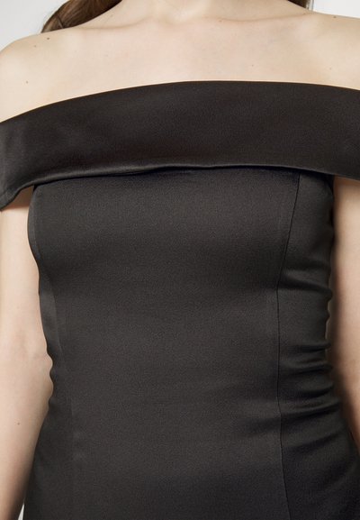 Vestito nero a spalle scoperte realizzato in tessuto liscio, con una silhouette aderente e dettagli arricciati sui lati.
