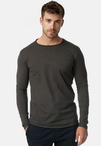 Camisa de manga larga, de color verde oscuro, hecha de tela suave, con un escote redondo y un diseño ajustado, que presenta líneas limpias y un minimalismo en los detalles.