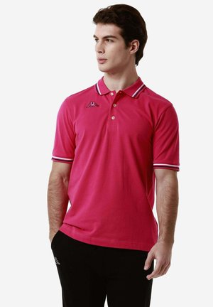 Polo shirt rosa con colletto e polsini a righe bianche e blu navy. Presenta un logo sul lato sinistro del petto. Realizzato in tessuto morbido e liscio.
