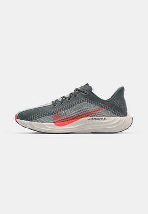 Nike running shoe featuring a breathable gray mesh upper, red accents, sleek design, and a white cushioning sole marked with "ZoomX."