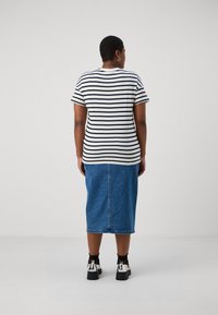 Stripet svart og hvit t-skjorte, korte ermer, kombinert med en denimskjørt til kneet og svarte og sølv plattformsko.