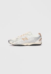 Sneaker da sport in grigio chiaro con accenti argentati, tomaia in rete, dettagli beige e suola in gomma nera. Presenta lacci e colletto imbottito.
