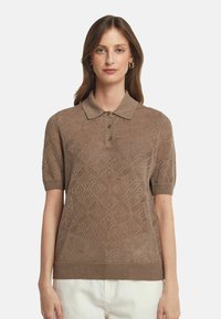 Brunstickad polo med korta ärmar, med ett strukturerat diamantmönster och tre knappar vid kragen. Mjuk, andningsbar material.