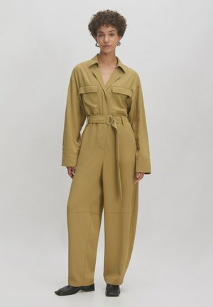Combinaison légère vert olive avec une taille ceinturée, de grandes poches poitrine et des jambes larges. Fabriquée en tissu lisse et légèrement brillant.