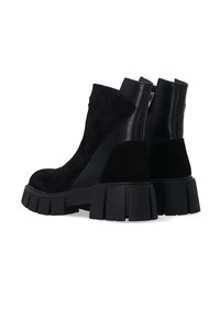 Zwarte enkellaarsjes van suede en leer, met een chunky platformzool, ronde neus en ritssluiting aan de achterkant.