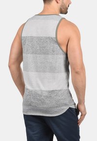 Gestreiftes Tanktop in Grau und Hellgrau mit abgerundetem Saum, aus einem weichen Stoff; verfügt über breite Armausschnitte und ein schlichtes Design.