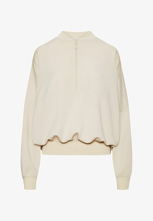 Beżowa krótka bluza z długimi rękawami, półzamkiem z przodu, elastycznym dołem i prążkowanymi mankietami.