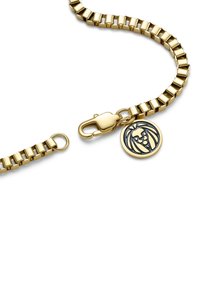 Gold-tone metal bracelet with articulated links, featuring a lobster clasp and a round charm with a black lion design.