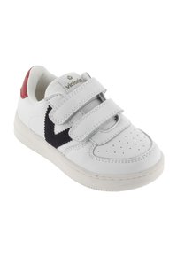 Baskets blanches en cuir avec des sangles Velcro, motif accent en bleu marine, onglet de talon rouge et design de pointe perforé. Logo de la marque sur la languette.