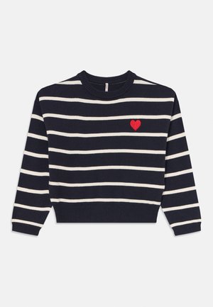 Granatowy sweter z poziomymi białymi paskami i małym czerwonym sercem wyszytym na górnej lewej części klatki piersiowej.