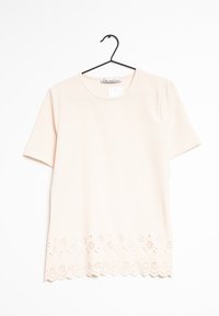 Top leggero rosa chiaro a maniche corte con scollatura rotonda e motivo floreale a intaglio all'orlo. Tessuto morbido con una sottile trama.