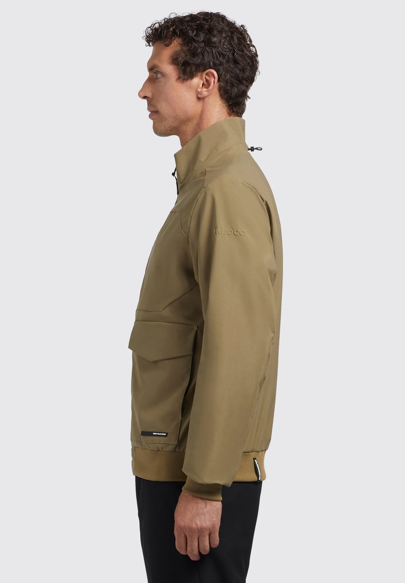 Veste légère marron avec un col haut, fermeture éclair sur le devant, poignets élastiques et une grande poche avant. Texture lisse et détails de design minimalistes.