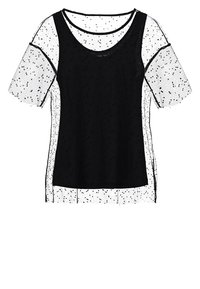 Top negro sin mangas, superpuesto a una blusa blanca transparente de manga corta con pequeños lunares negros y escote redondo.