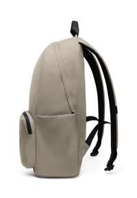 Beige ryggsäck med en slät yta, stort huvudfack, sidofack med dragkedja, vadderade remmar och ett handtag på toppen.