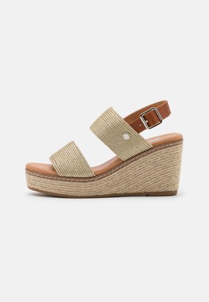 Kilesandal med beige vævede stropper, justerbar brun læderankelrem med spænde og tekstureret jute platformssål.
