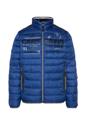 Isolierte blaue Steppjacke mit hohem Kragen, Reißverschluss, Seitentaschen und textlichen Druckmotiven in Schwarz und Weiß auf der Vorderseite.