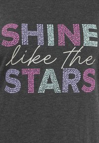 T-shirt grigia con testo a pois colorati che recita "BRILLA come le STELLE" in rosa pastello, viola e blu. Tessuto liscio.