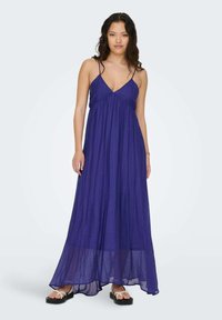 Larga vestido maxi sin mangas en púrpura intenso, con escote en V, tejido fluido y un corte relajado. Combínalo con sandalias planas.