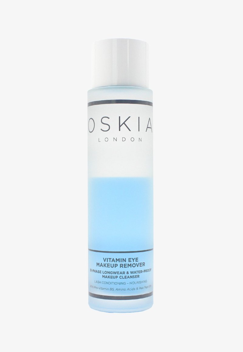 Bouteille cylindrique transparente contenant un liquide bleu, étiquetée "Oskia Démaquillant pour les Yeux à la Vitamine", avec du texte noir et blanc et un capuchon blanc.