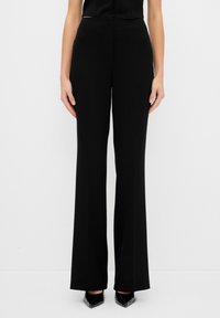 Pantalones de pierna ancha negros con cintura alta, diseñados en una tela suave. Presentan una silueta limpia y combinan bien con varias blusas.