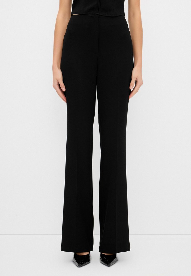 Pantalones de pierna ancha negros con cintura alta, diseñados en una tela suave. Presentan una silueta limpia y combinan bien con varias blusas.