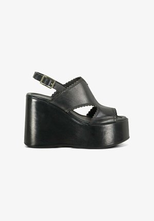Sandale compensée en cuir noir avec bride à la cheville et détail bord festonné sur la tige et les côtés.
