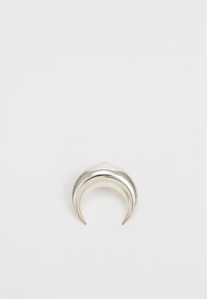 Anillo plateado en forma de media luna con una textura pulida y bordes suaves y curvados, creando un diseño minimalista.