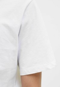 Hvid bomulds T-shirt med rund hals og korte ærmer. Glat tekstur med en enkel, klassisk snit og afsluttede kanter.
