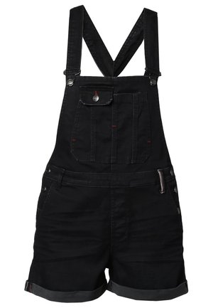 Personne portant une combinaison courte en denim noir, un t-shirt à manches longues gris, des collants noirs transparents, des bottines noires et un sac à dos noir.