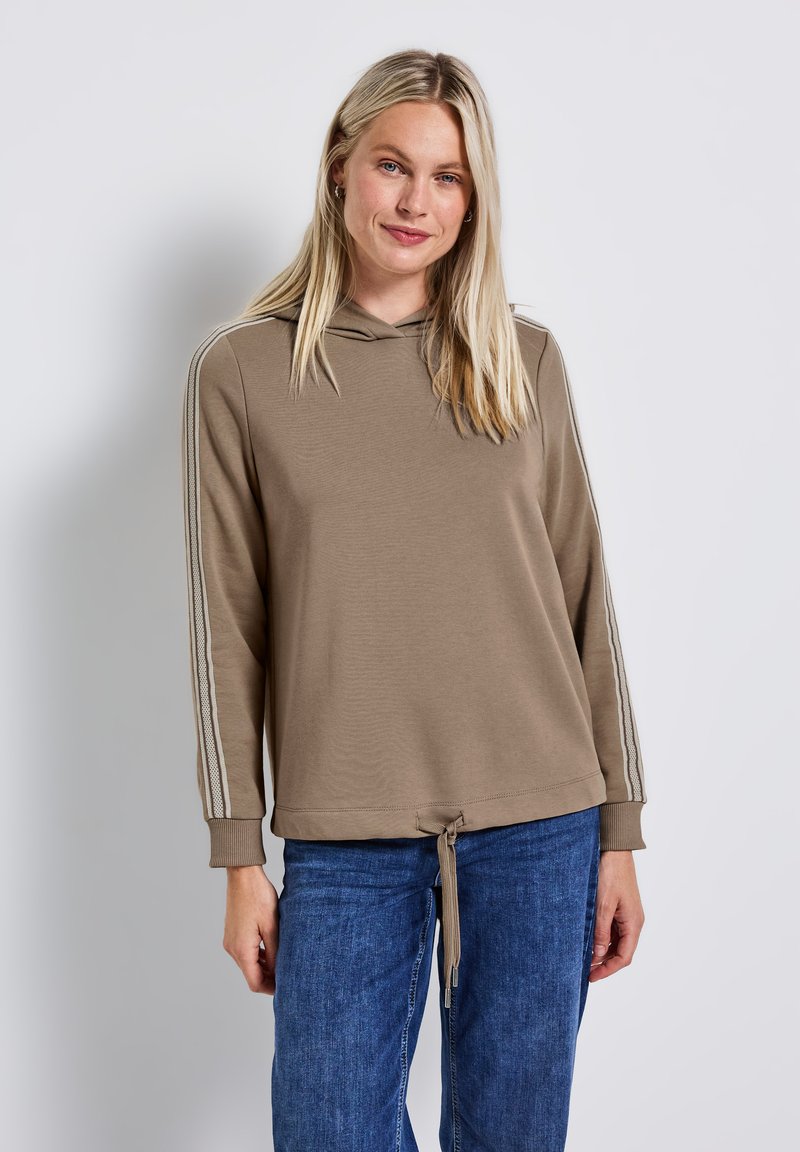 Felpa marrone con coulisse sull'orlo, caratterizzata da strisce verticali sulle maniche, realizzata in tessuto morbido. Indossata con jeans di denim blu.