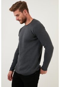 Cămașă gri cu mânecă lungă, din material ribbed, cu decolteu rotund și un design ajustat, având cusături contrastante și un tiv ușor curbat.