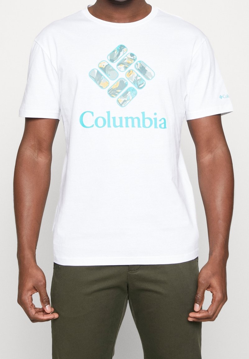 Vit bomullströja med en turkos och flerfärgad Columbia-logotypgrafik på framsidan. Kortsleeves och rundad halsdesign.